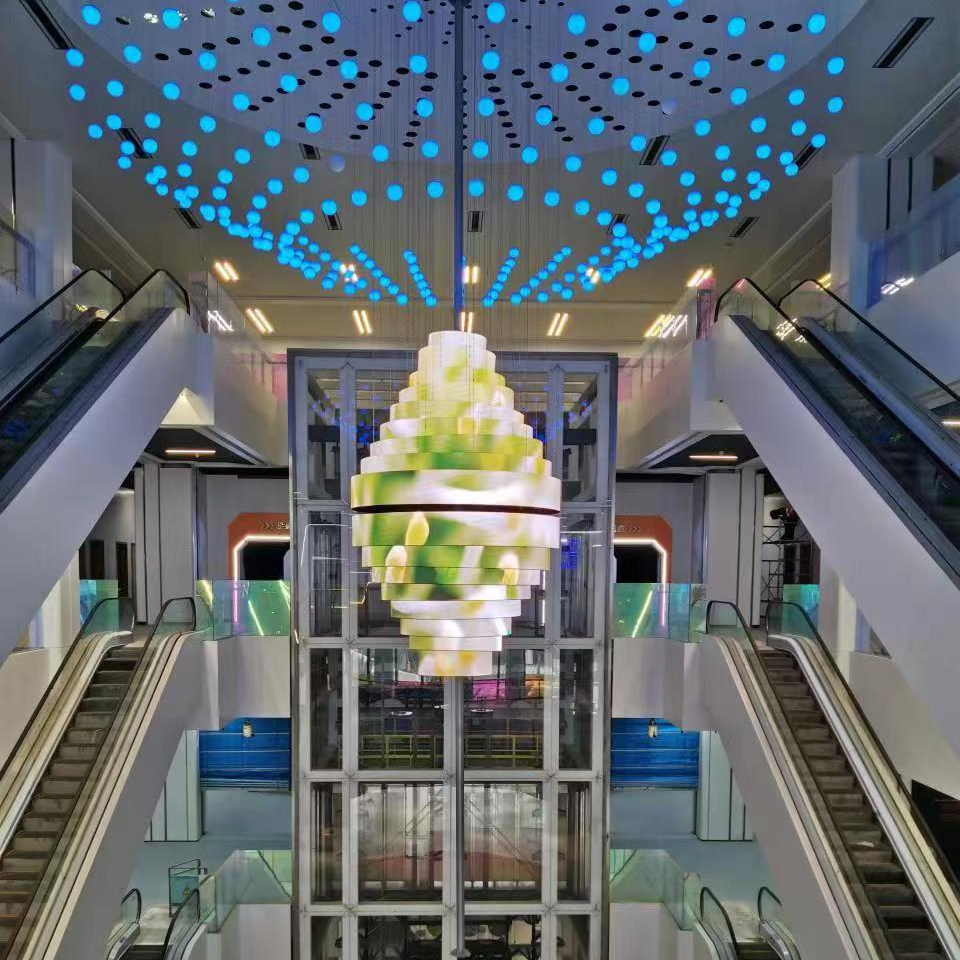 The application of led soft module constructed cone-shaped led display hanging on the top of the shopping mall, with chandeliers form a nice decoration.